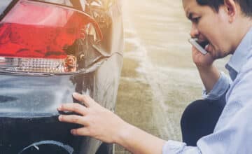 man is calling insurrance company claiming his car crash damaged road accident