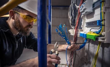 male electrician works switchboard with electrical connecting cable