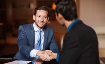 two happy partners shaking hands cafe