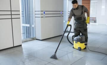 full shot man vacuuming office floor