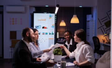 workaholics businesspeople brainstorming financial company ideas analyzing strategy paperwork late night business office meeting room
