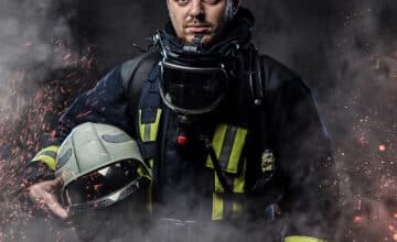 professional firefighter dressed uniform holding safety helmet fire sparks smoke dark background