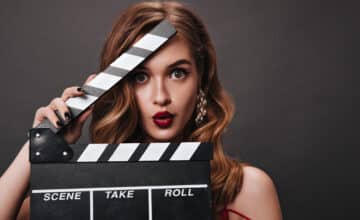 greeneyed lady silk bright dress holding clapperboard whistling
