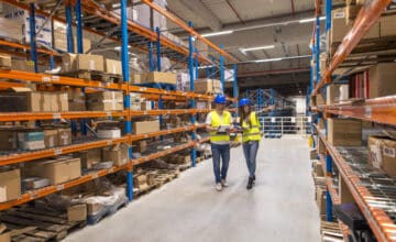 two warehouse workers walking distribution storage area discussing about logistics organization